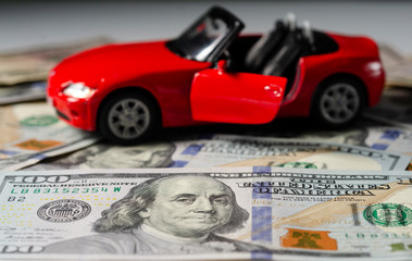 Bright, sports car in red on a background of dollars