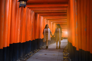 Fototapeta premium woman traveller walks enjoy in the red post column row together, Autumn season change blooming on popular and famous place for tourist visit Japan