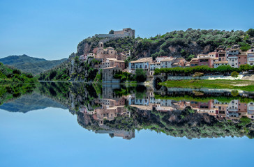 Fototapeta na wymiar Reflections in the Ebro of the town of Miravet in Tarragona