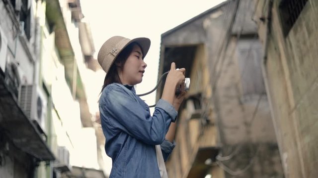 Attractive asian woman traveler wearing retro fedora hat use film camera taking a photo. Enjoying traveling on vacation summer. Solo travel concept.