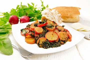 Radish with spinach and spices in plate on light wooden board