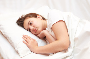 sick girl lying in white bed with a thermometer. . coronavirus