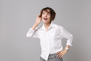 Curious young business woman in white shirt posing isolated on grey wall background studio...