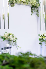 Wedding ceremony arch white decor with flowers and green leaves