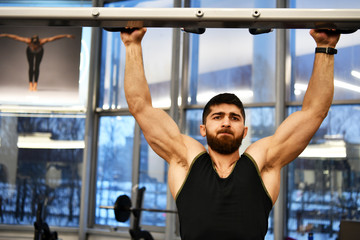 male athlete doing physical exercises for the development of the body in the gym