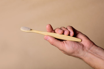 Close up of man's hand holding bamboo toothbrush
