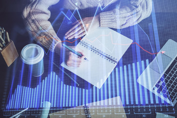 Forex graph on hand taking notes background. Concept of research. Double exposure