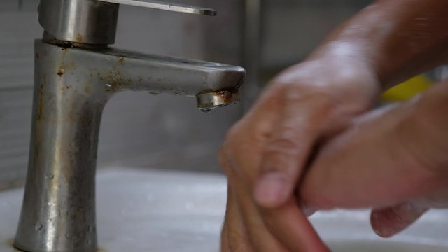 Person rinsing hands, handwashing in bathroom, washing hand with soap under water flow. Royalty high-quality best stock footage of closeup washing hands, handwashing with soap and water under faucet