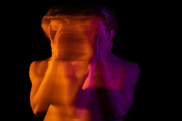 young handsome man naked torso. Closing face with hands. Long exposure artistic portrait. Orange and pink. dreamy drama artistic look. 