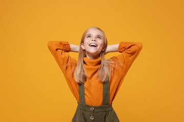 Obraz na płótnie Canvas Pensive little blonde kid girl 12-13 years old in turtleneck, jumpsuit isolated on orange yellow wall background. Childhood lifestyle concept. Mock up copy space. Looking up with hands behind head.