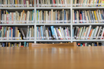 Wooden table with bookshelves in library - Powered by Adobe