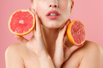 Close up shot cropped blonde half naked woman 20s perfect skin nude make up hold in hand grapefruit isolated on pastel pink background studio portrait. Skin care healthcare cosmetic procedures concept