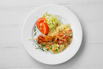 Top view of plate with chicken shashlik, rice with peas and cabbage salad