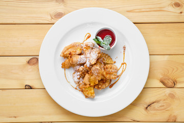 Top view of plate with deep fried fruits in breading served with caramel and strawberry jam
