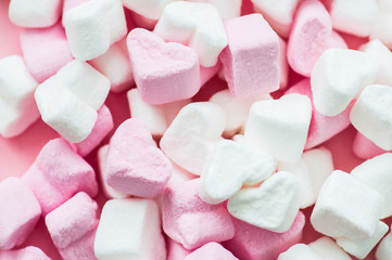 Pink fluffy heart shaped marshmallows candy background.