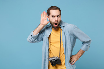 Curious traveler tourist man in yellow summer clothes with photo camera isolated on blue...