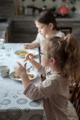Two girls eat at a table in the kitchen