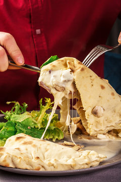 Cheese that stretches. Cheese in dough. Focaccia with cheese. Calzone with cheese. The hand that takes the piece. restaurant ambiance