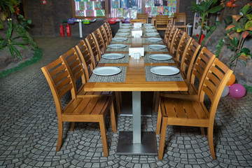 modern restaurant interior, table with cutlery, plate, glass, napkins and orchids on the table.Restaurant or home kitchen design lifestyle concept . Outdoor backyard wooden dining table setup .