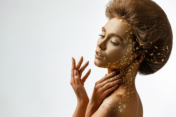 Fashion art portrait of model girl with holiday golden shiny professional makeup. woman with gold...