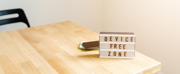 Digital detox day. Lightbox on wooden background and white walls. Gadget ban