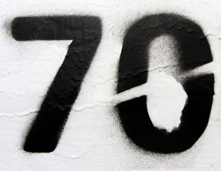 Number 70 black sprayed digit on rust painted white metal surface