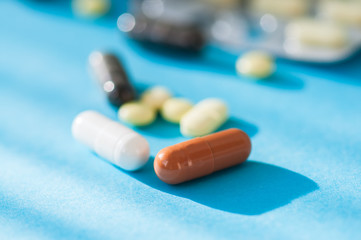 Close up of assorted medicine pills and tablets on a blue background.