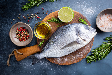 Fresh ready to cook raw bream fish dorado with ingredients and seasonings like rosemary, salt,...