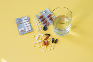 Top view of assorted medicine pills and tablets, medical mask and glass of water. Copy space.