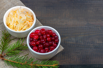 Sauerkraut or fermented cabbage with cranberries on rustic wooden background. The concept of proper nutrition and healthy eating. Organic and vegetarian food contain vitamin c. Close up, copy space