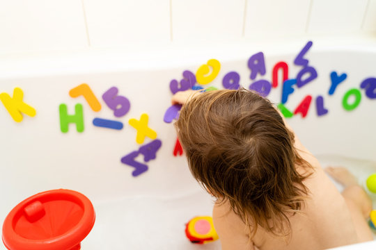 Little girl is playing foam lettern in the bath. Learning abc with play. Montessori activity
