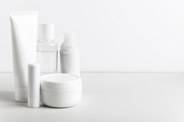 Facial and body care cosmetics bottles composition on white background. Gel tube, lipstick, cream...