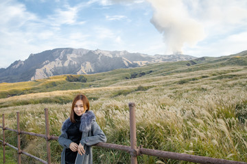 Fototapeta na wymiar Lonely girl in Area of Aso active volcano background with smoke at Mount Aso Nakadake, Kumamoto, kyushu, Japan. (Photo grain some noise on film colour)