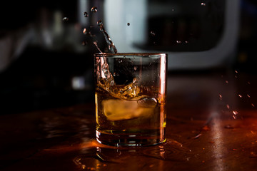 Whiskey With Ice Served in a Bar and Splashes out of Glass