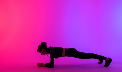  sports girl on a bright color background stands in the plank