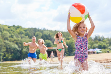 Girl is running with a ball in the sea