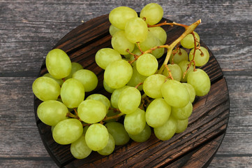 Green grapes on a wooden background. Flat lay. view from above. Place for writing. Juicy bunch of grapes on a wooden background.