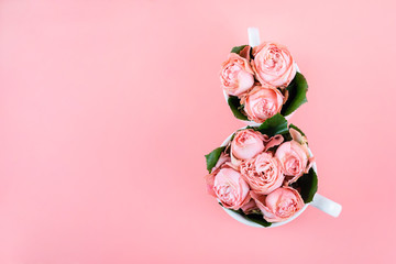 Top view with two cups of coffee with pink flowers of the copy space. Background for women's day on March 8. Pink table. A woman and a stylish workplace. March 8 and the concept of " Women's day&raquo;