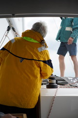 Two men Captain with yellow jacket and first mate on sailboat © Sahara Frost