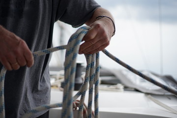 Close up of hands coiling up a rope, sheet on a sailboat