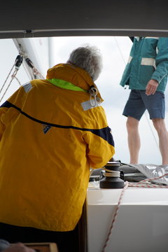 Two men Captain with yellow jacket and first mate on sailboat
