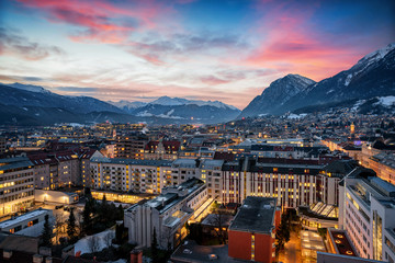 Panoramablick auf Innsbruck in den Alpen Österreichs im Winter am Abend nach Sonnenuntergang mit Schnee und Wolken - obrazy, fototapety, plakaty