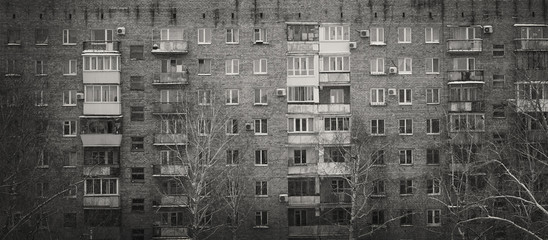 closeup facade  of a brick old multi-storey building, typical serial development, black and white photo