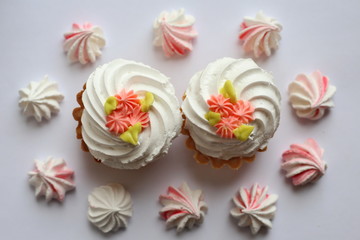 Cake with whipped cream and meringue. White, slightly grayish background. White green rose cream. Tartlet-shaped cake. Cake decorated with cream flowers 