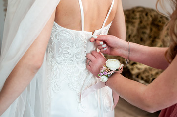 Bridesmaids assist bride to wear wedding dress