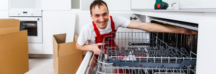 Repairman examining dishwasher with toolbox in kitchen