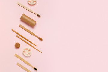 Zero waste concept. Natural bamboo toothbrush, craft tube, wooden sushi sticks, natural sponge on pink background. Flat lay, top view, copy space.