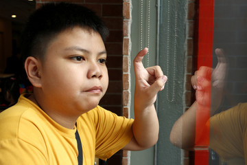 Young Asian boy looking out a glass window and