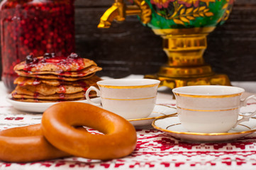 horizontal photo on a dark background. steering wheels in the foreground. copper samovar. Russian tea ceremony. two cups on a folk tablecloth.