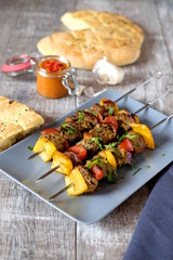drei spieße Schisch Kebab mit Lammfleisch Paprika und Zwiebeln auf grauem teller und Holztisch...